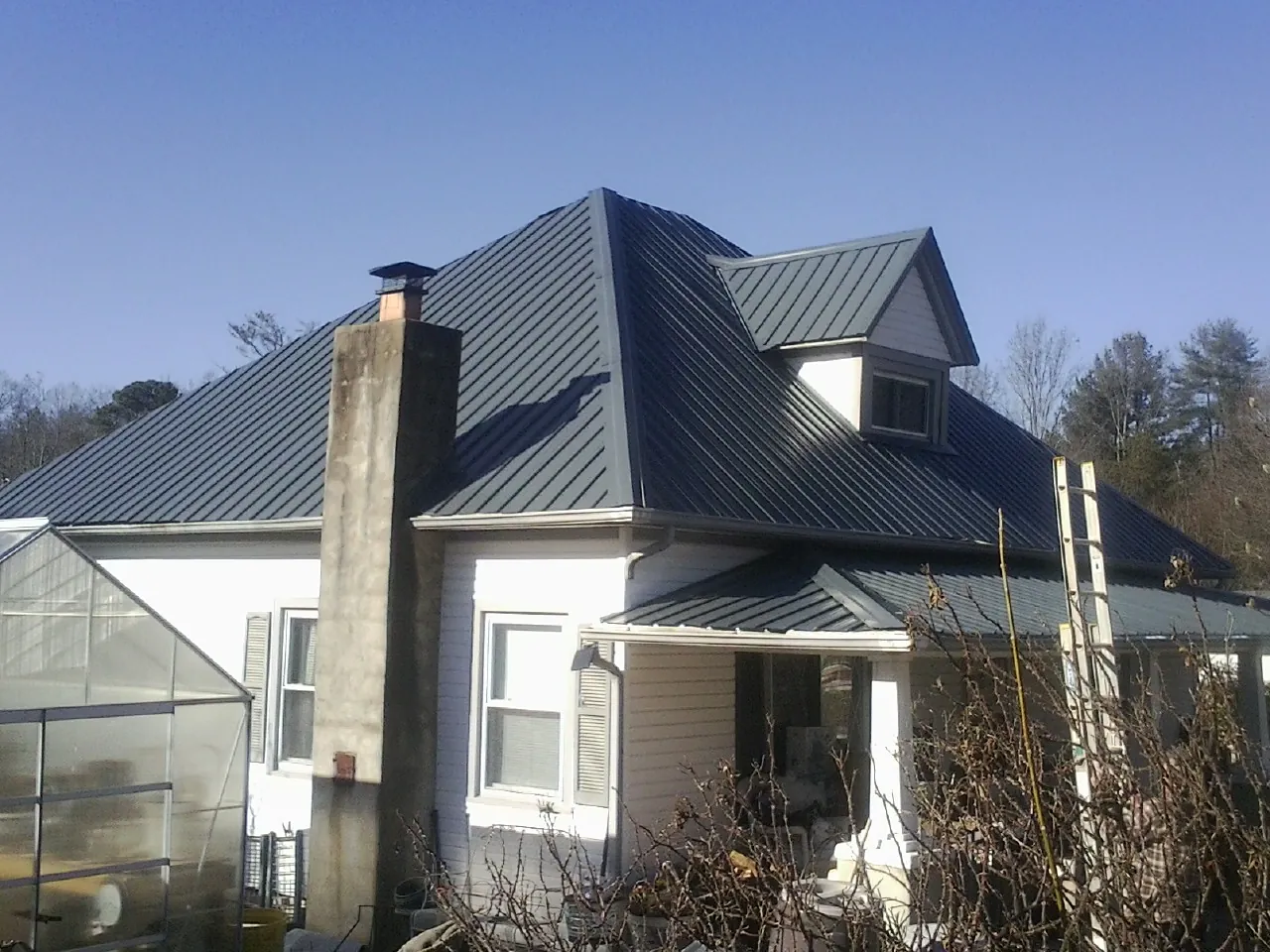 Dark blue standing seam metal roof on a white farmhouse with dormer — Slate & Tile Roof Repair by Roofing Brothers in Bardstown