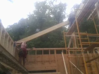 Carpenter raising a rafter beam on a new second story frame in Bardstown