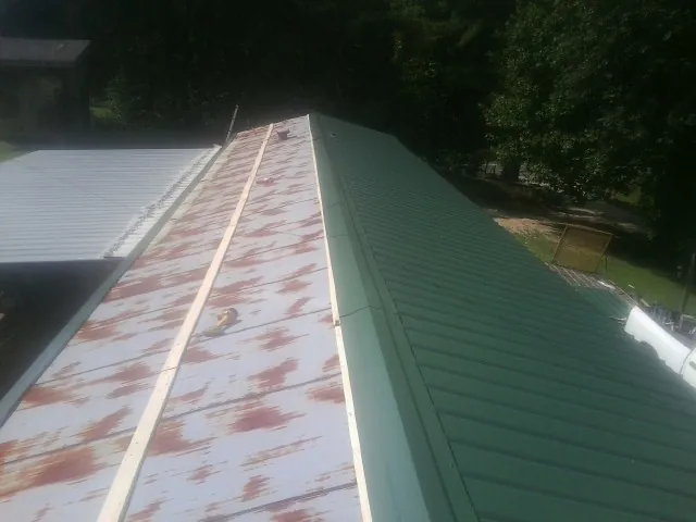 Old rusted panels beside newly installed green metal roofing — Wind Damage Roof Repair by Roofing Brothers in Bardstown
