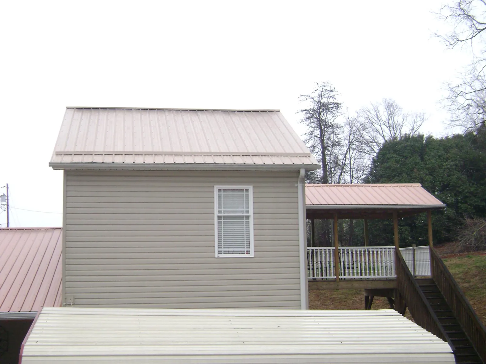 Tan metal roofs on a two story addition and attached porch, from a Roof Replacement job in Bardstown