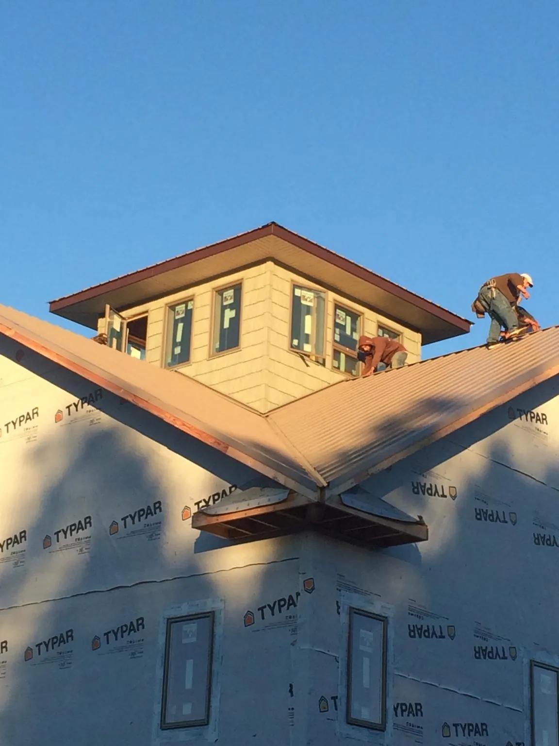 Roofers working around a rooftop cupola on a new metal roof at sunset — Roof Waterproofing in Bardstown by Roofing Brothers
